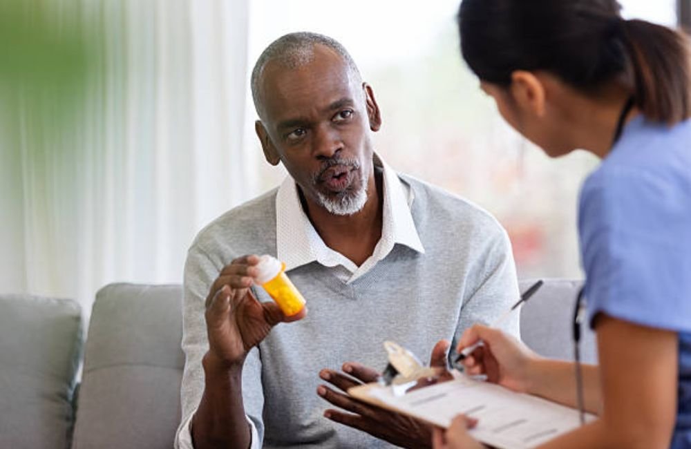 Man discussing his prescription bottle with a nurse during a medication review