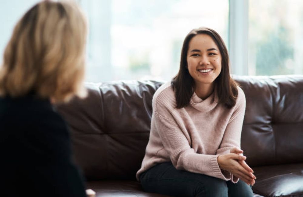 Woman sitting on a couch smiling during a residential mental health therapy session